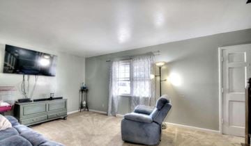 Rome house for rent - A living room with a grey couch, a grey chair, and a television mounted on the wall.