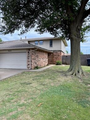 Oklahoma City apartment for rent - A house with a garage and a tree in front.
