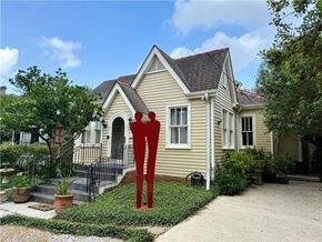New Orleans house for rent - A yellow house with a red sculpture in front.