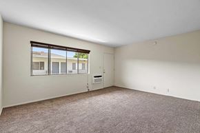 Burbank apartment for rent - A room with a carpeted floor and a window overlooking a building.