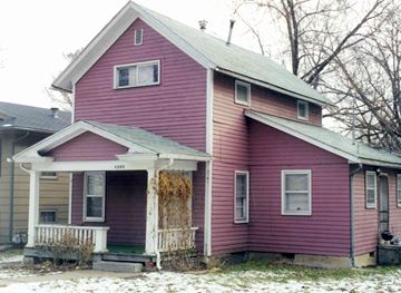 Lawrence apartment for rent - A red house with a white porch and a yellowish snow on the ground.