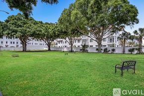 Tampa apartment for rent - A grassy area with trees and benches in front of a white building.
