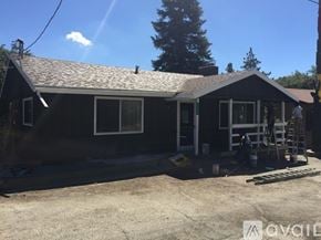 Idyllwild Pine Cove house for rent - A house with a black roof and white trim is under construction with a ladder and tools on the porch.