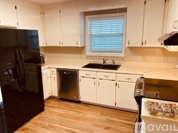 Dothan house for rent - A kitchen with white cabinets and a black refrigerator.
