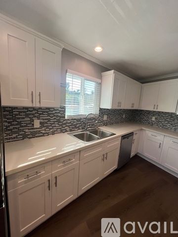 San Diego house for rent - A kitchen with white cabinets and a black and white tiled backsplash.