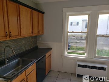 New Bedford apartment for rent - A kitchen with wooden cabinets and a window overlooking a parking lot.