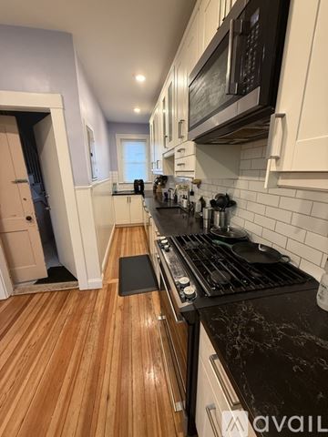 Brookline apartment for rent - A kitchen with a black counter top and wooden floors.