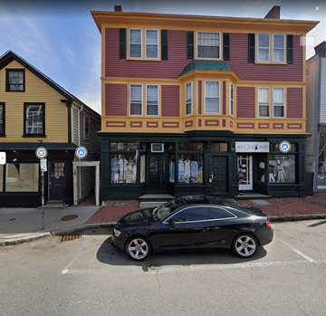 Marblehead apartment for rent - A black car is parked in front of a building with a red and yellow facade.