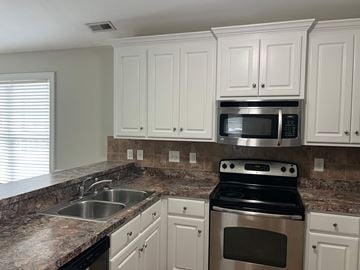 Wilson house for rent - A kitchen with granite countertops and white cabinets.