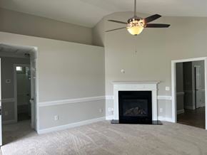 Wilson house for rent - A living room with a fireplace and a ceiling fan.