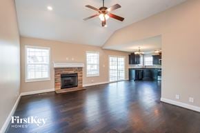 Clarksville house for rent - A spacious living room with a fireplace and a ceiling fan.