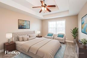 Clarksville house for rent - A bedroom with a large bed, a ceiling fan, and a painting on the wall.