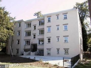 Washington apartment for rent - A tall building with many windows is surrounded by trees.