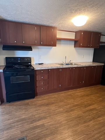 Grinnell house for rent - A kitchen with wooden cabinets and a black stove top oven.