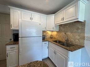 Seminole house for rent - A kitchen with white cabinets and a granite countertop.