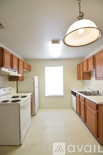 Killeen apartment for rent - A kitchen with brown cabinets and a white stove top oven.