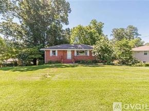 Smyrna house for rent - A red house with a white door and windows is surrounded by green grass and trees.