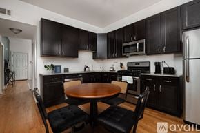 Chicago apartment for rent - A kitchen with black cabinets and a wooden table.