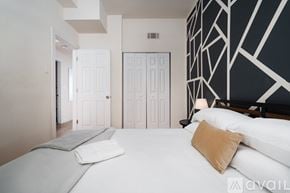 Chicago apartment for rent - A bedroom with a large bed and a black and white geometric wallpaper.