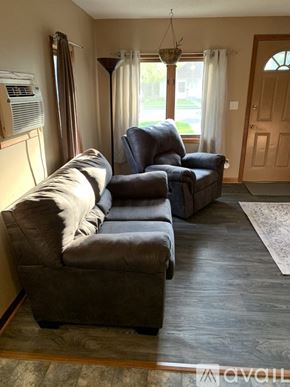 Bemidji house for rent - A living room with a grey couch and a black chair.