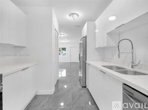 Miami house for rent - A modern kitchen with white cabinets and a grey floor.