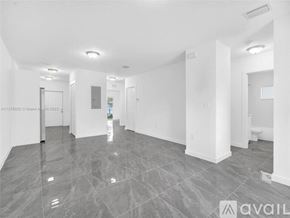 Miami house for rent - A spacious, empty room with grey tiled flooring and white walls.