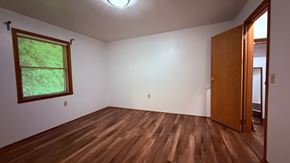 Sitka house for rent - A room with a wooden floor and a window with a view of trees.
