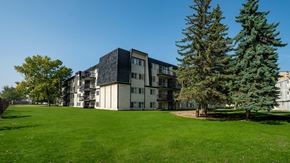 Edmonton apartment for rent - A large grassy area in front of a building with trees.
