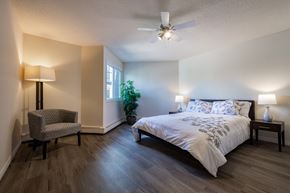 Edmonton apartment for rent - A bedroom with a bed, chair, and plant.