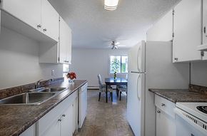 Edmonton apartment for rent - A kitchen with white cabinets and a table with chairs.