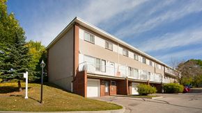 Calgary apartment for rent - A building with a red brick base and beige upper floors with white trim.