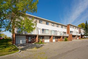 Calgary apartment for rent - A large apartment building with a parking lot in front.