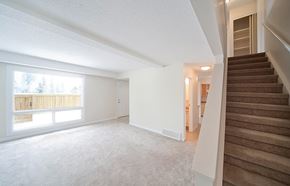 Edmonton apartment for rent - A spacious room with a staircase leading to another room.