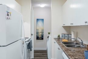 Edmonton apartment for rent - A kitchen with a white fridge and a painting of a sunset on the wall.