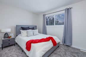 Edmonton apartment for rent - A bedroom with a large bed and a red blanket.