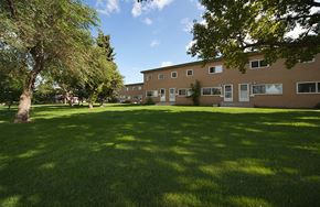 Edmonton apartment for rent - A grassy area in front of a building with trees.