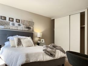 Edmonton apartment for rent - A bedroom with a bed, a lamp, a wall art, and a chair.