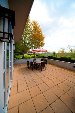 Burnaby apartment for rent - A patio with a table and chairs is seen from a window.