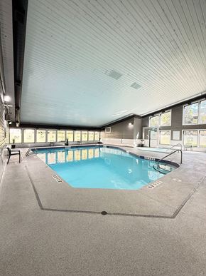 Edmonton apartment for rent - A large indoor swimming pool with a blue tiled edge and a metal ladder.