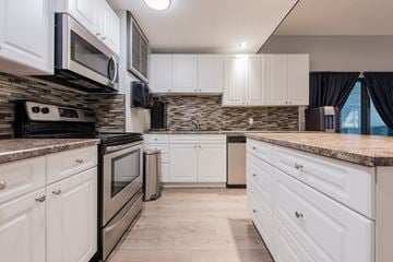 Edmonton apartment for rent - A kitchen with white cabinets and a stone backsplash.