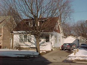 East Lansing apartment for rent - A white house with a brown roof and a tree in front.