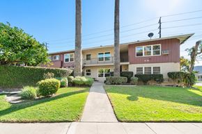 Burbank apartment for rent - A red and beige two-story house with a green lawn in front.