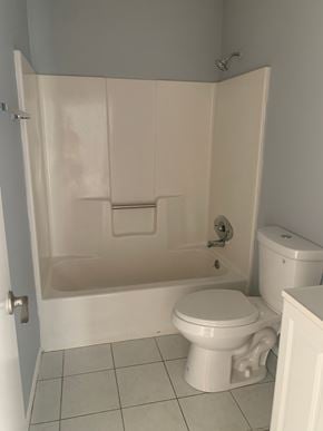 Pensacola house for rent - A white toilet sits next to a walk-in shower.