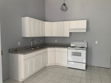 Pensacola house for rent - A kitchen with white cabinets and a granite countertop.