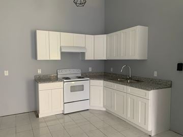 Pensacola house for rent - A kitchen with white cabinets and appliances.