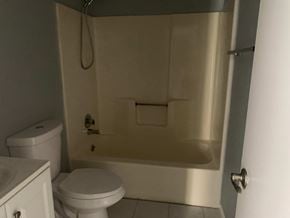 Pensacola house for rent - A white toilet sits next to a white sink in a small bathroom.