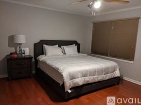 Atlanta townhouse for rent - A bedroom with a large bed and a nightstand with a lamp.