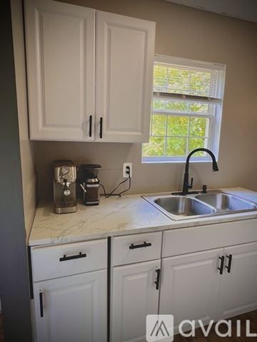 Seneca house for rent - A kitchen with white cabinets and a marble countertop.