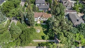Winnipeg house for rent - A large house with a circular garden in front is surrounded by trees.