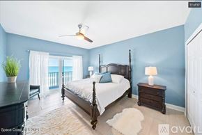 Melbourne Beach apartment for rent - A bedroom with a large bed, a ceiling fan, and a window with curtains.